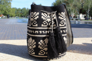 Medium-sized black and cream bag with woven designs and black tassels.